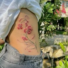 a woman's lower back tattoo with pink flowers on her stomach and behind her