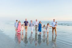 a group of people standing on top of a beach next to the ocean