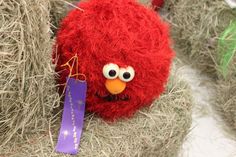 a red stuffed animal sitting in hay with a tag on it's ear and eyes