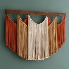 the wall hanging is made out of wood and has different colored fringes on it