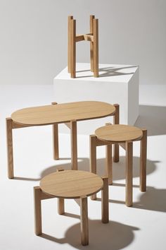 three wooden tables sitting next to each other on top of a white surface and one is empty