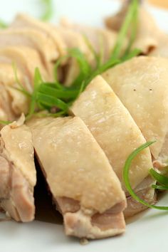 sliced meat on a white plate with green garnish