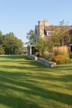 an image of a house that is in the middle of some grass with trees and bushes around it