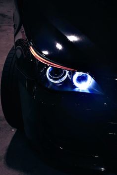 the front end of a black car with blue lights on it's headlight