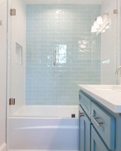 a bathroom with blue cabinets and a white bathtub next to a walk in shower