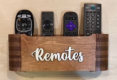 remotes are sitting in a wooden holder with the word remotes written on it