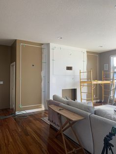 a living room with hard wood flooring and walls being built in the back ground