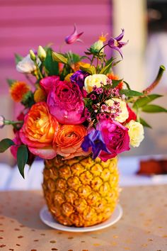 a pineapple vase filled with colorful flowers on top of a table