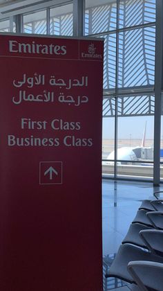 a red sign in an airport that says emirates first class business class