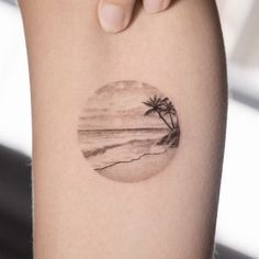 a person with a small tattoo on their arm that has a palm tree in the middle