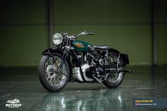 an old motorcycle is parked in a dark room with green walls and concrete flooring