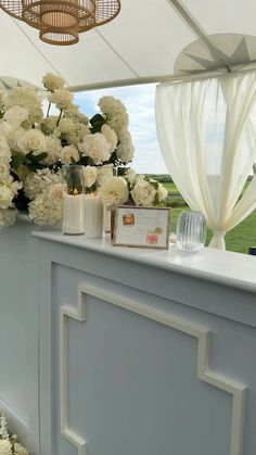 white flowers and candles are on display under a canopy at an outdoor wedding reception in the sun