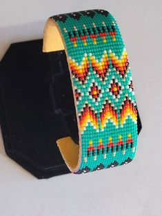 a beaded bracelet is sitting on a black stand