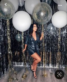 a woman standing in front of balloons and streamers with her leg up on the floor