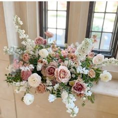 a vase filled with lots of pink and white flowers next to a window sill