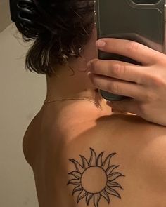 a woman with a sun tattoo on her back taking a selfie in the mirror