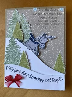 a christmas card with a horse on top of a hill and pine trees in the background