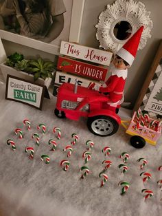 an elf is riding on a toy tractor with candy canes in front of him