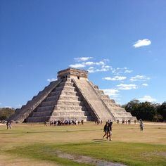 people walking around in front of an ancient pyramid on a sunny day with blue skies