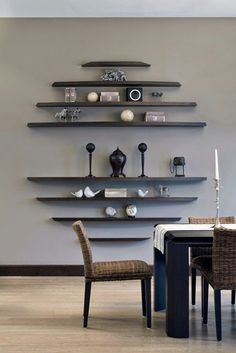 a dining room table with chairs and shelves on the wall in front of it,