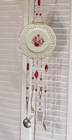 a plate and spoons hanging from a hook on a wall with white shutters