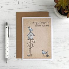 a card with a birdhouse on it next to a pen