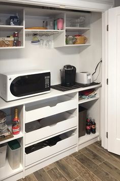 a microwave oven sitting on top of a white counter next to a shelf filled with bottles