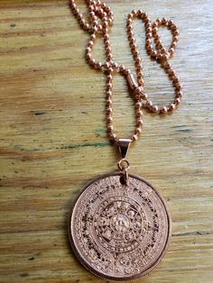 "Copper Aztec Calendar Necklace This pendant necklace is made from a 1 ounce 999 copper round, a copper pendant bail, copper jump rings, and your choice of a 3.2mm copper bead chain or 4.4mm stainless steel chain. The pendant/coin is 39mm or roughly 1.5\" in diameter. Because these are handmade, no two pendants will be exactly the same. The Aztec Calendar or Aztec Sun Stone is a famous sculpture housed in the National Anthropology Museum in Mexico City, Mexico. Images of the calendar appear on Mexican coins, is used in artwork, and is seen in pop culture. All prices include free shipping within the United States. Shipping outside of the U.S. will add additional cost to the purchase price." Symbolic Copper Pendant Jewelry, Symbolic Round Bronze Necklace, Nickel-free Rose Gold Copper Necklace, Symbolic Copper Jewelry As Gift, Symbolic Copper Jewelry For Gifts, Adjustable Copper Necklace With Round Pendant, Symbolic Copper Jewelry Gift, Symbolic Nickel-free Copper Jewelry, Adjustable Copper Round Pendant Necklace