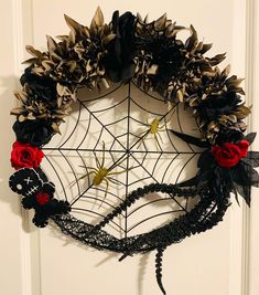 a spider web wreath decorated with black and red flowers