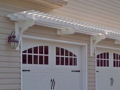 two white garage doors with arched windows on the side of a house