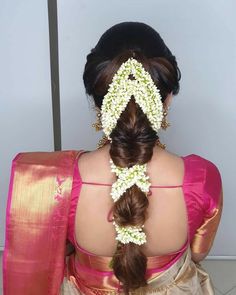 the back of a woman's head with braids and flowers in her hair