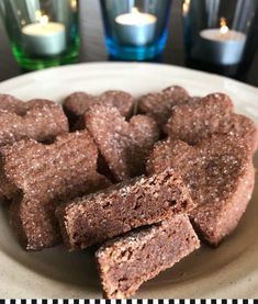 some brownies are on a plate with candles in the background