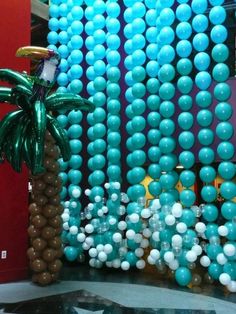 balloons and palm trees are displayed in front of a wall made out of blue and white balls