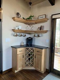 a kitchen with wooden cabinets and shelves filled with wine glasses, coffee mugs and other items