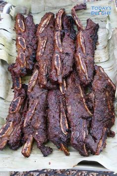 several pieces of meat sitting on top of a wooden tray next to other food items