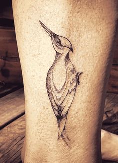 a small tattoo on the leg of a person with a bird in it's beak