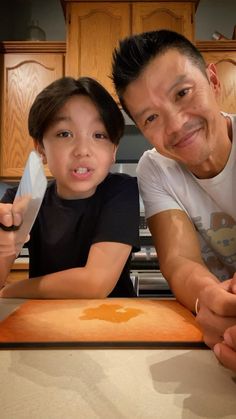 a father and son posing for a photo in the kitchen