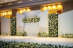 a stage set up with flowers and greenery on the side for a wedding ceremony