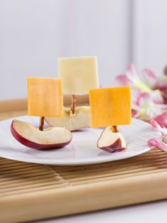 slices of cheese and apples on a white plate with pink flowers in the back ground