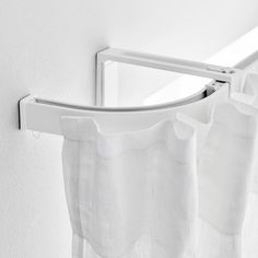 a white shower curtain hanging on the side of a wall