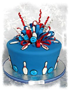 a blue cake decorated with bowling pins and ribbons