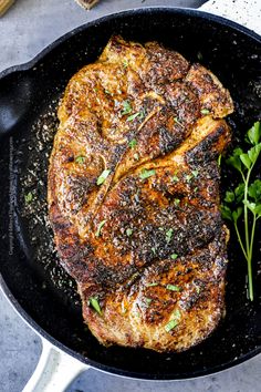 two pieces of meat in a skillet with parsley