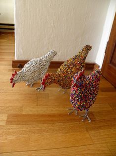 three birds made out of sprinkles sitting on the floor in front of a wall