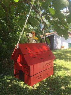 a red dog house hanging from a tree