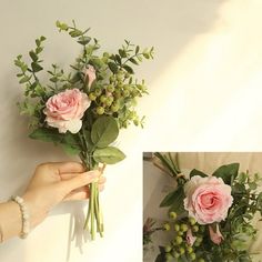 a person holding flowers in their hand and another flower arrangement on the wall behind them