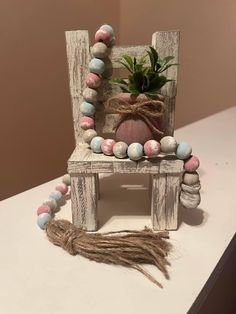 a wooden chair with beads and a potted plant on it's back sitting on a table