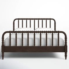 a wooden bed frame with white sheets and pillows on it's headboard, in front of a plain background