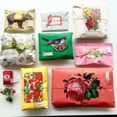 six wrapped presents with flowers and birds on them, all tied up in different colors