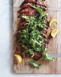 steak with greens and lemons on a cutting board