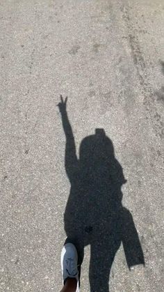 the shadow of a person's hand on asphalt